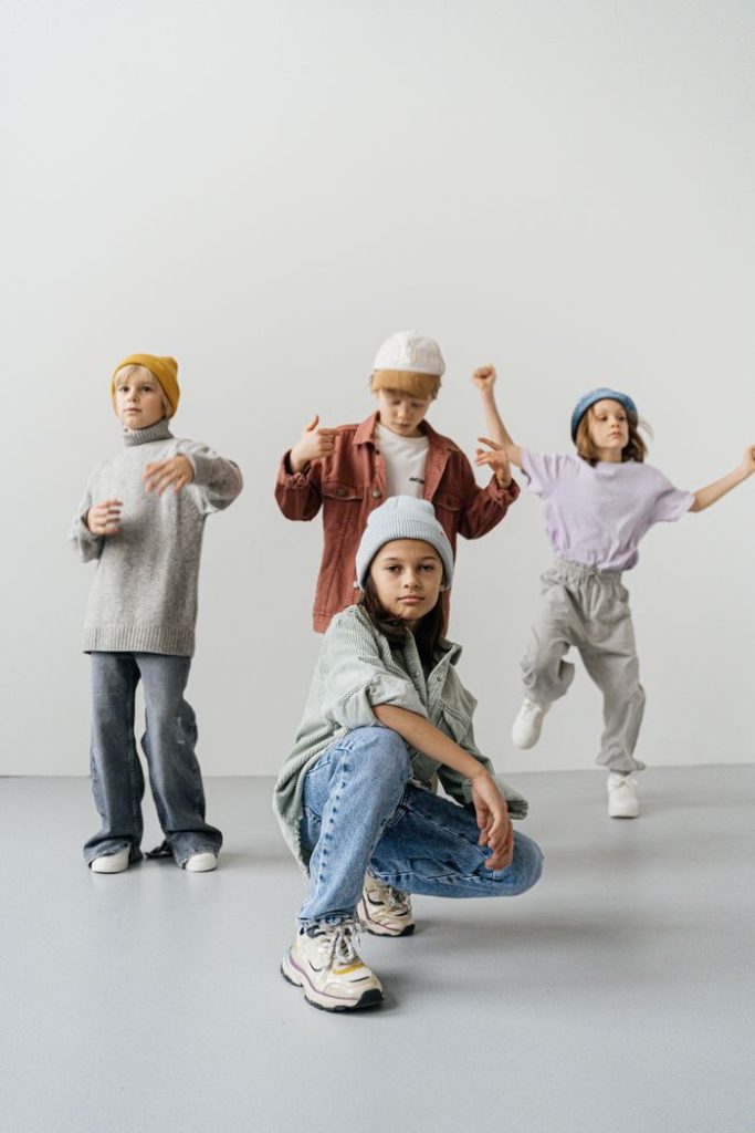 Group of stylish children posing in modern fashion outfits against a white background.